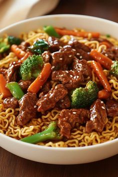 a white bowl filled with beef and broccoli on top of noodle noodles