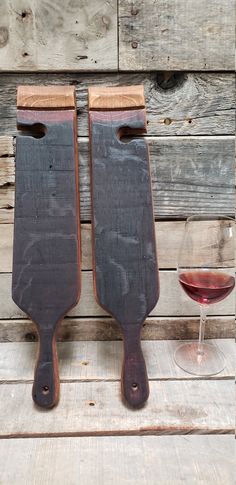 two wooden paddles sitting next to a glass of wine