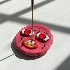 a pink object with two eyes and one eyeball sticking out of it's mouth