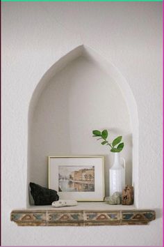 there is a vase and some rocks on the shelf in front of this wall niche