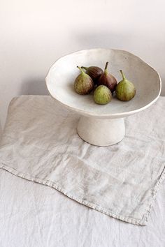 three figs in a white bowl on a table