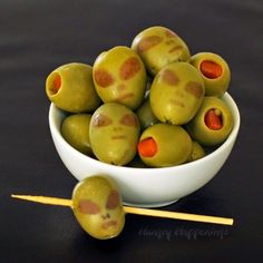 some olives are in a white bowl with toothpicks