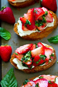 strawberries and cream on top of toasted bread with spinach leaves around it