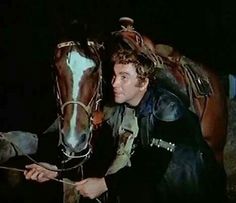 a man standing next to a horse in the dark with his hand on it's bridle