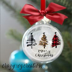 a glass ornament with christmas trees on it and a red ribbon hanging from the top