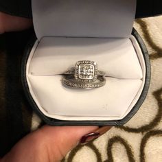 a woman's hand holding an engagement ring in a box