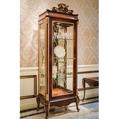 an antique china cabinet with glass doors and ornate carvings on the top, in a room with wallpapered walls