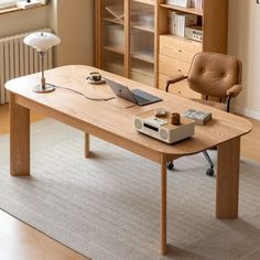 a wooden table with a laptop on it in front of a bookshelf and window