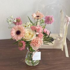 a vase filled with lots of pink and white flowers on top of a wooden table