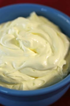 a blue bowl filled with cream on top of a red table