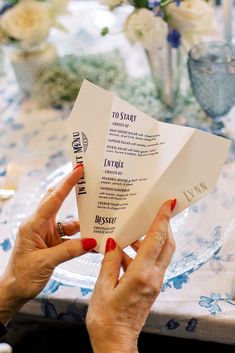 a woman holding up some paper at a table