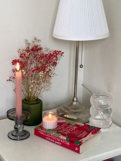 a white table topped with a lamp next to a vase filled with flowers and books