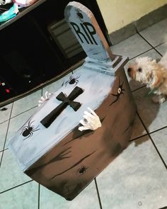 a dog standing next to a cardboard box with a cross on it's side