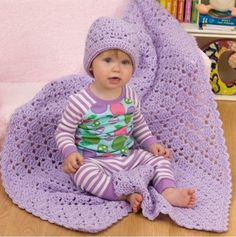 a baby sitting on the floor wearing a purple hat