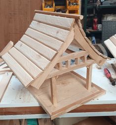 a wooden house sitting on top of a table next to some woodworking tools and plywood