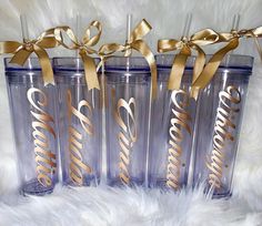 three personalized tumblers with gold ribbon and name written on the side, sitting next to each other