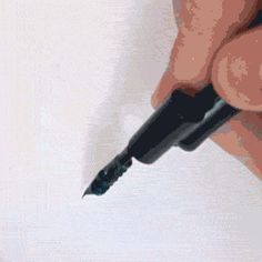 a person holding a pen in their left hand and writing on the paper with it