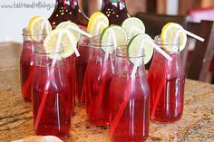 several glasses filled with red liquid and lemons