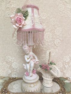 a pink lamp sitting on top of a table next to a white vase with flowers