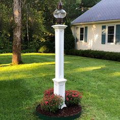 a white lamp post in the middle of a flower bed