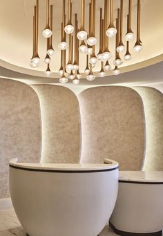 two large white vases sitting next to each other in front of a chandelier