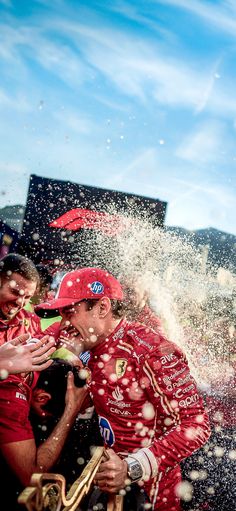 two men in red racing suits splash water onto each other