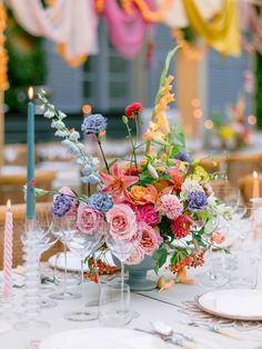 a vase filled with flowers sitting on top of a table next to wine glasses and candles