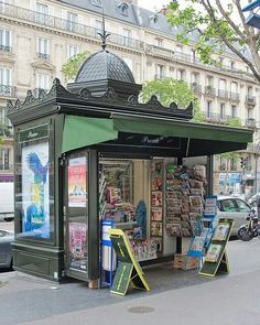 a small kiosk on the side of a street with a green awning