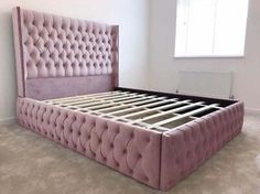 a pink bed frame with buttons on the headboard and foot board in a bedroom