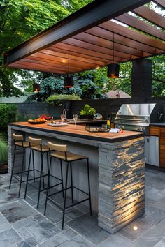 an outdoor kitchen with stone counter tops and bar stools next to the grill area