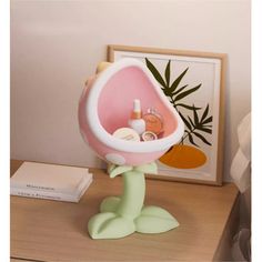 a pink and white flower vase sitting on top of a table next to a book