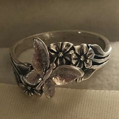 a silver ring with flowers on it sitting on top of a white cloth covered table