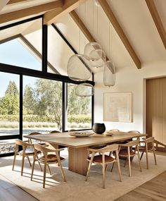 the dining room table is surrounded by wooden chairs and large windows with glass panes