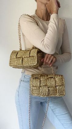 a woman is posing with her hand on her shoulder and holding a gold purse in front of her face