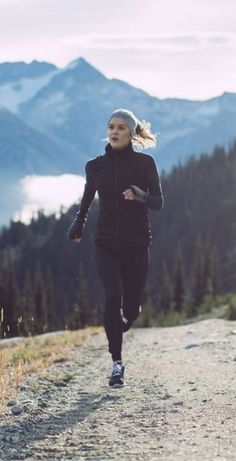 a woman running on a trail in the mountains