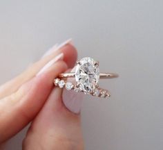 a woman's hand holding an engagement ring with two diamonds on top of it