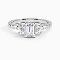 an emerald cut diamond ring with three baguets on the band and side stones