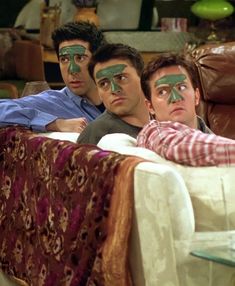 three men with painted faces laying on a couch