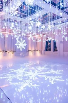 an indoor dance floor with snowflakes hanging from the ceiling and lights on it