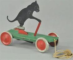 an old fashioned toy car with a cat on the front and side wheel attached to it