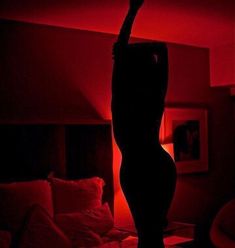 a woman standing in the middle of a bed with red light on her head and arms