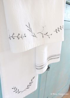 two white towels hanging on a blue cabinet