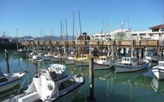 many boats are docked in the water near a pier