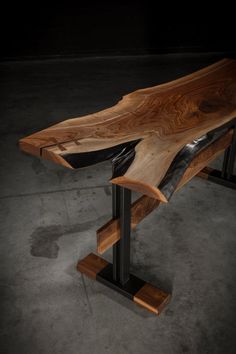 a wooden table with black metal legs and a wood slab on the top that is shaped like a cross