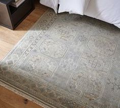 a bed with a large gray rug on top of it next to a night stand