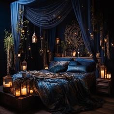 a bed covered in blue sheets and pillows with lit candles on the floor next to it