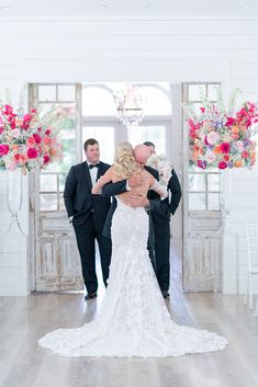 the bride and groom are kissing in front of their wedding ceremony arch with pink flowers