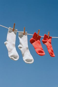 three pairs of socks hanging on a clothes line with blue sky in the back ground