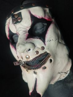 a white mask with black and red designs on it's face, zippered around the mouth