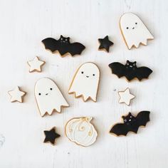 decorated halloween cookies arranged in the shape of ghostes and bats on a white table